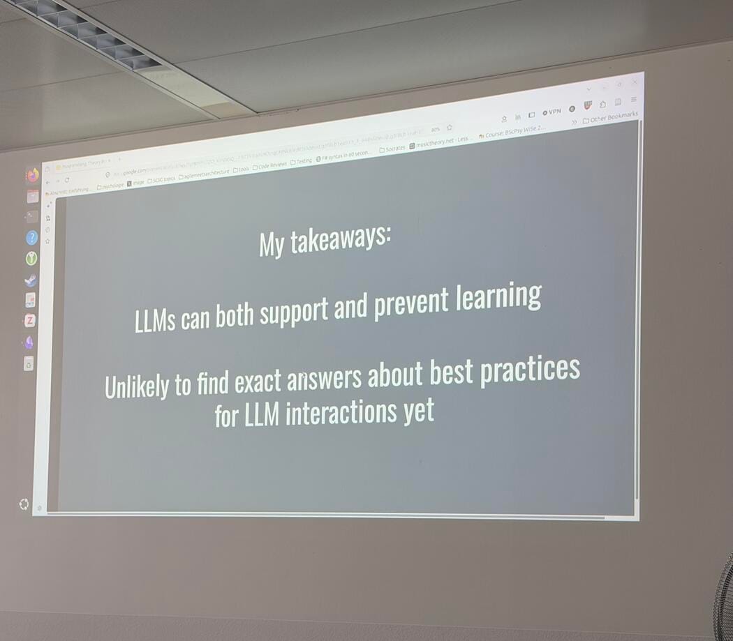 A projector screen shows a slide reading 'My takeaways. LLMs can both support and prevent learning. Unlikely to find exact answers about best practices for LLM interactions yet.'
